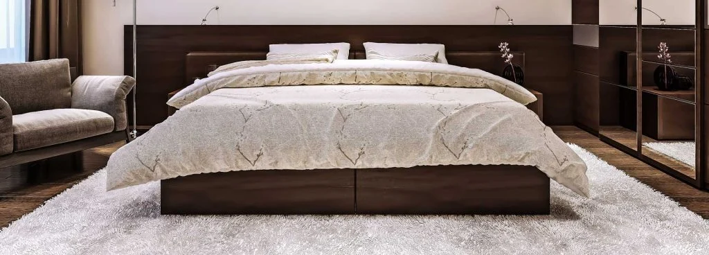 A large bed with a cream cover in a bright bedroom