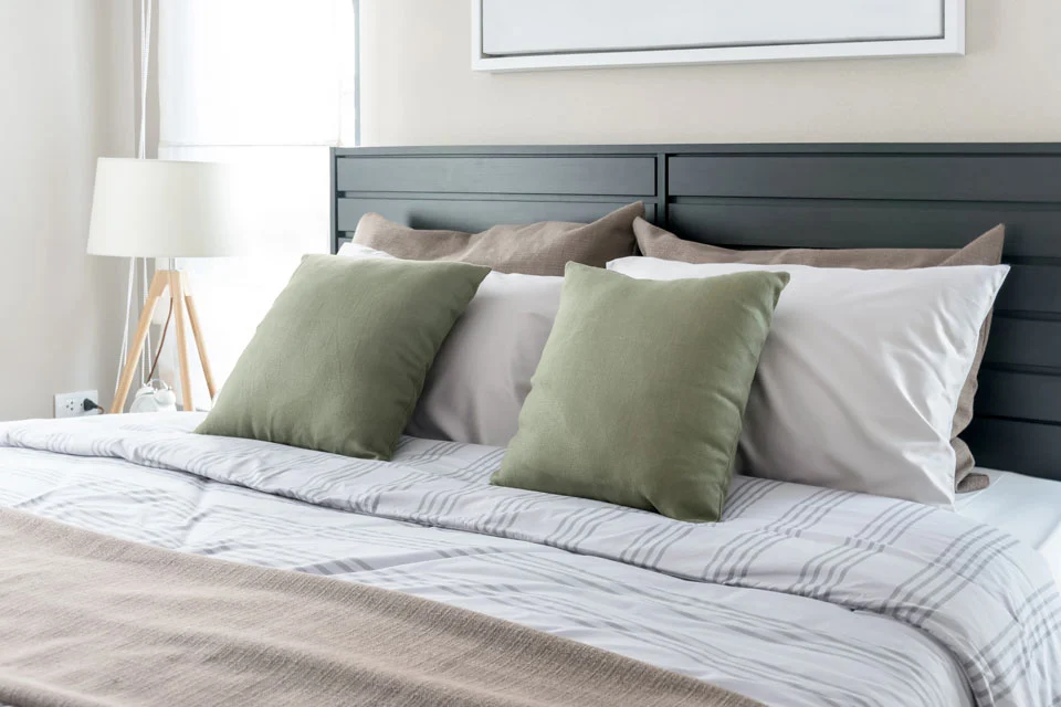 A freshly made bed with green pillows