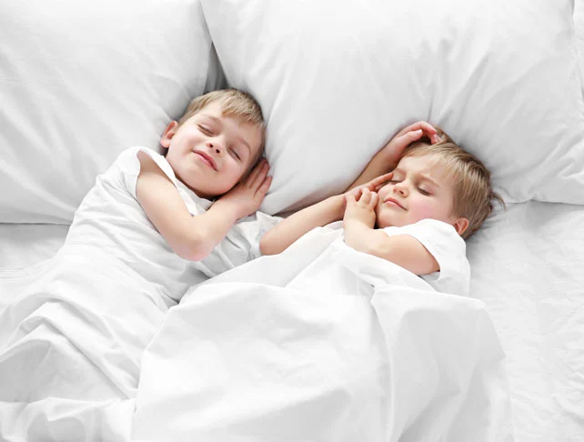 Two children asleep on fresh white sheets
