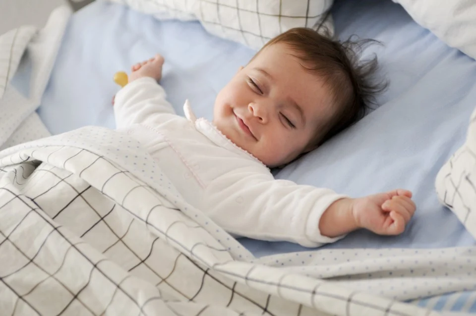 A smiling baby lying on a soft blue sheet